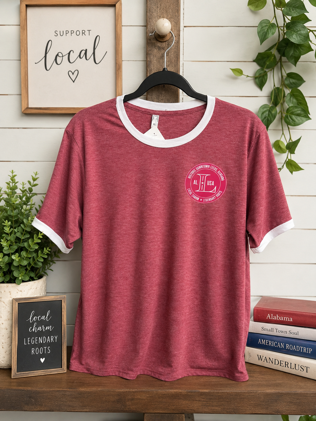 A heathered dusty rose short-sleeve t-shirt with white ribbed collar and sleeve cuffs, hanging on a black hanger. The shirt features a pink circular graphic on the left chest with the letters 'HF' and 'Hershey's Friends'.