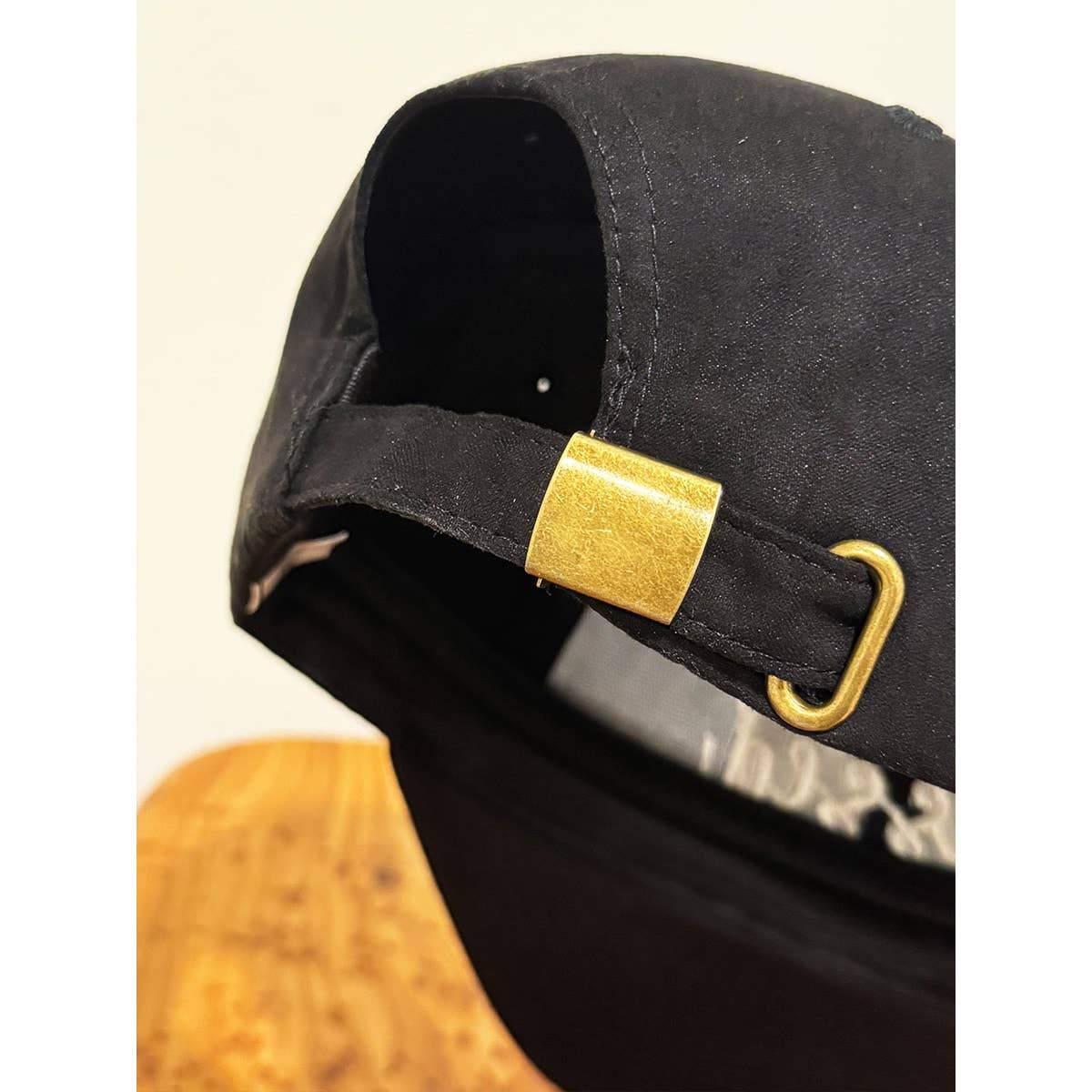 Black cap with a gold buckle on a beige background