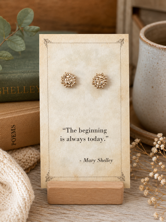 Gold tone sun and moon face stud earrings displayed on a vintage Mary Shelley literary quote card