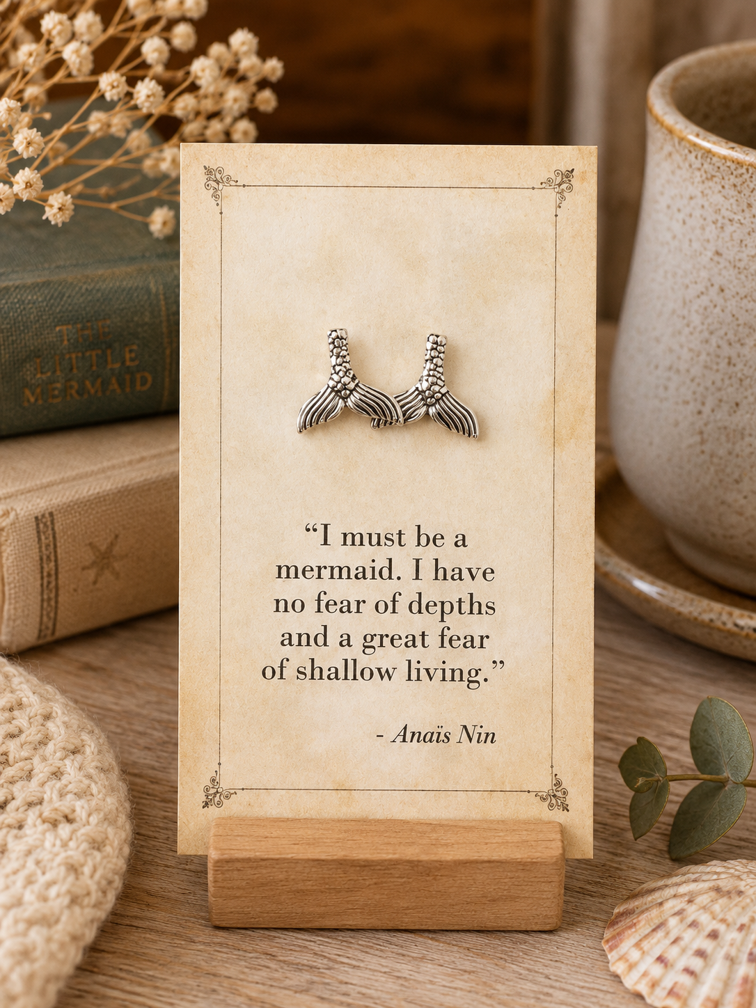 Silver tone mermaid tail stud earrings displayed on a vintage literary quote card
