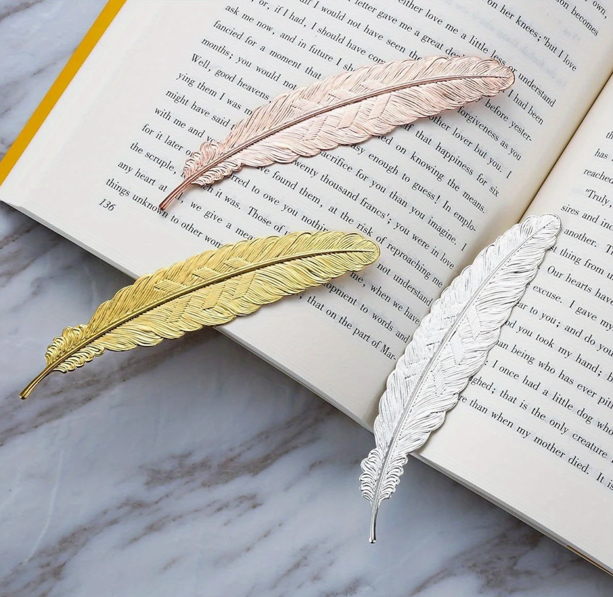 Metal bookmark shaped like a feather with a sleek, antique finish—perfect for readers and gift-giving.