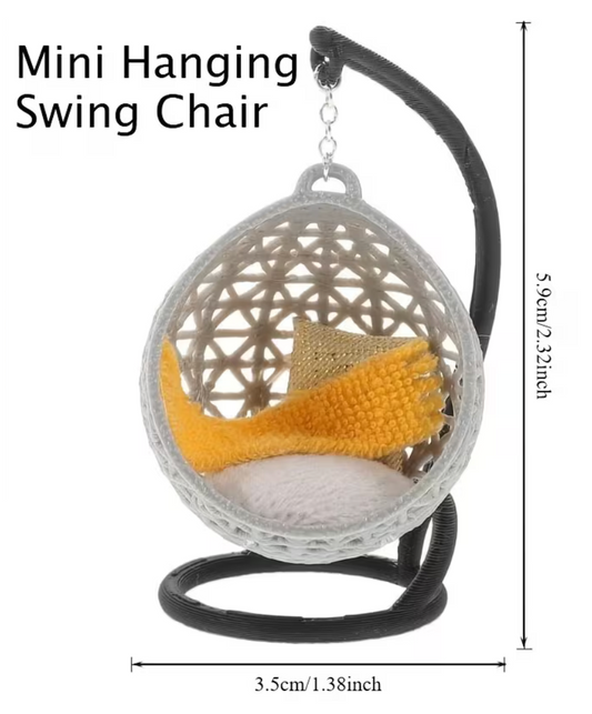 Mini hanging swing chair miniature with gray woven egg chair, black stand, white cushion, and yellow accent pillow for dollhouse and fairy garden displays.