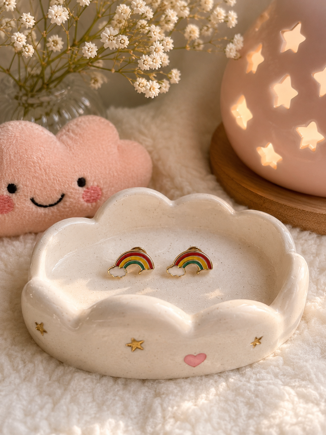 Minimalist rainbow stud earrings with enamel rainbow and cloud details displayed in a ceramic trinket dish