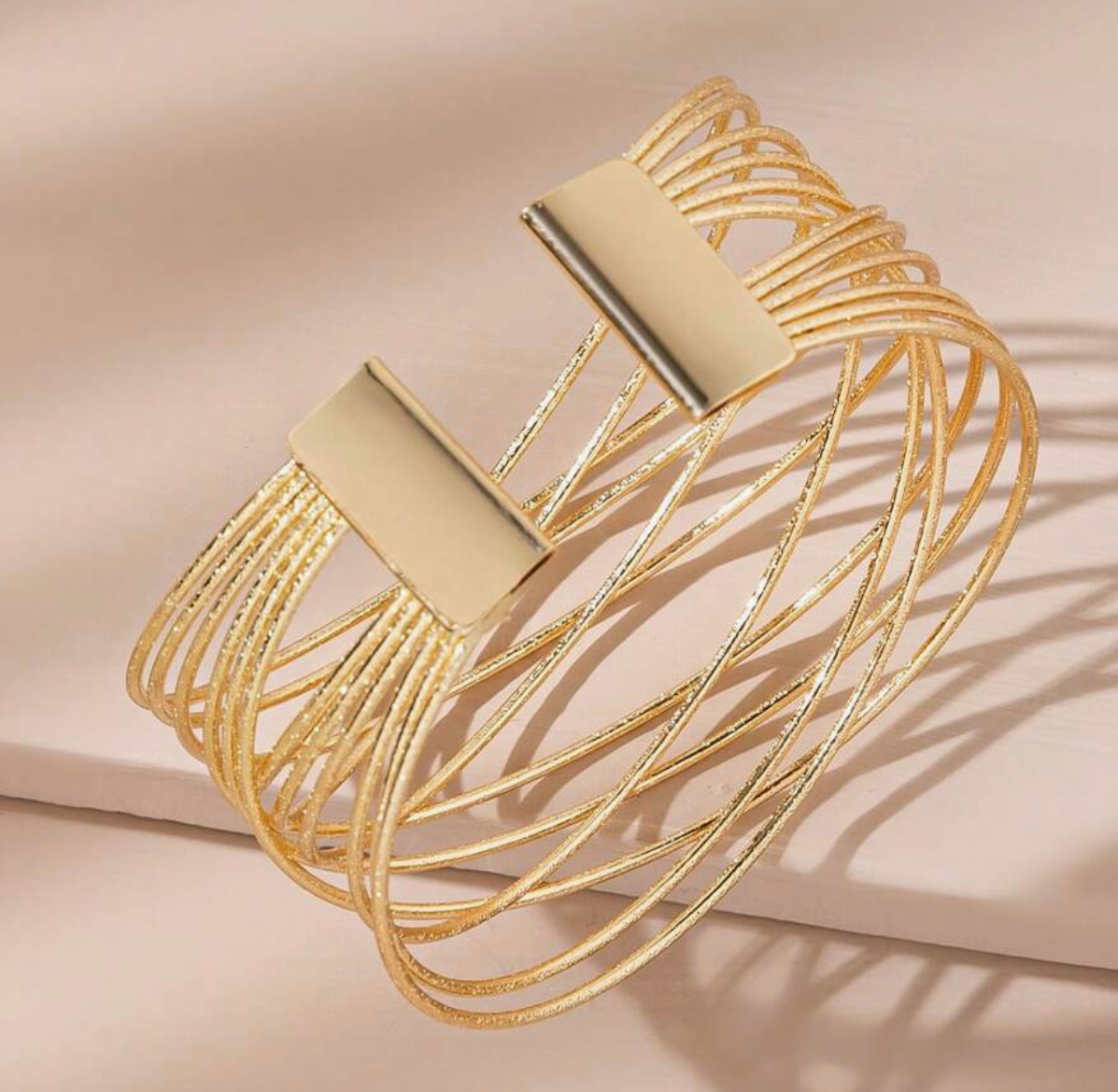 Gold bracelet with multiple loops on a beige background