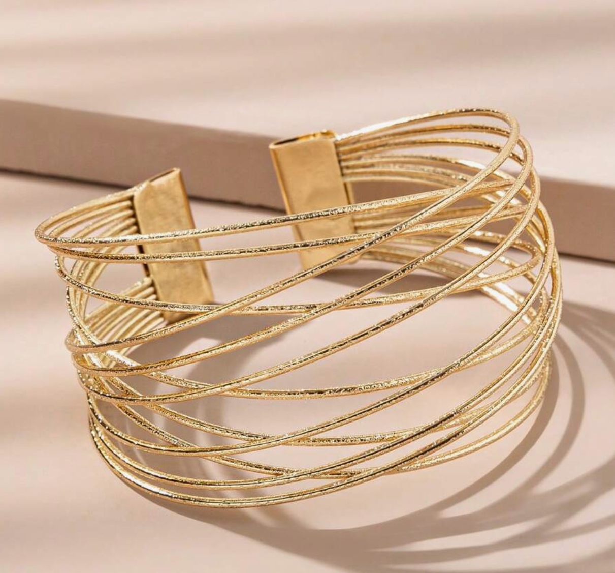 Gold bracelet with multiple loops on a beige background