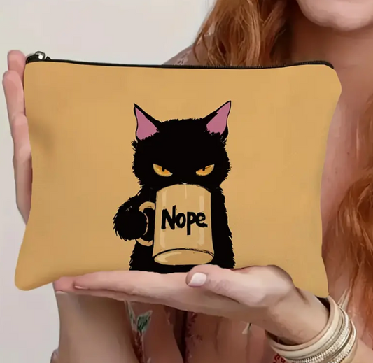 Person holding a yellow pouch with a black cat design holding a mug labeled 'Nope'.