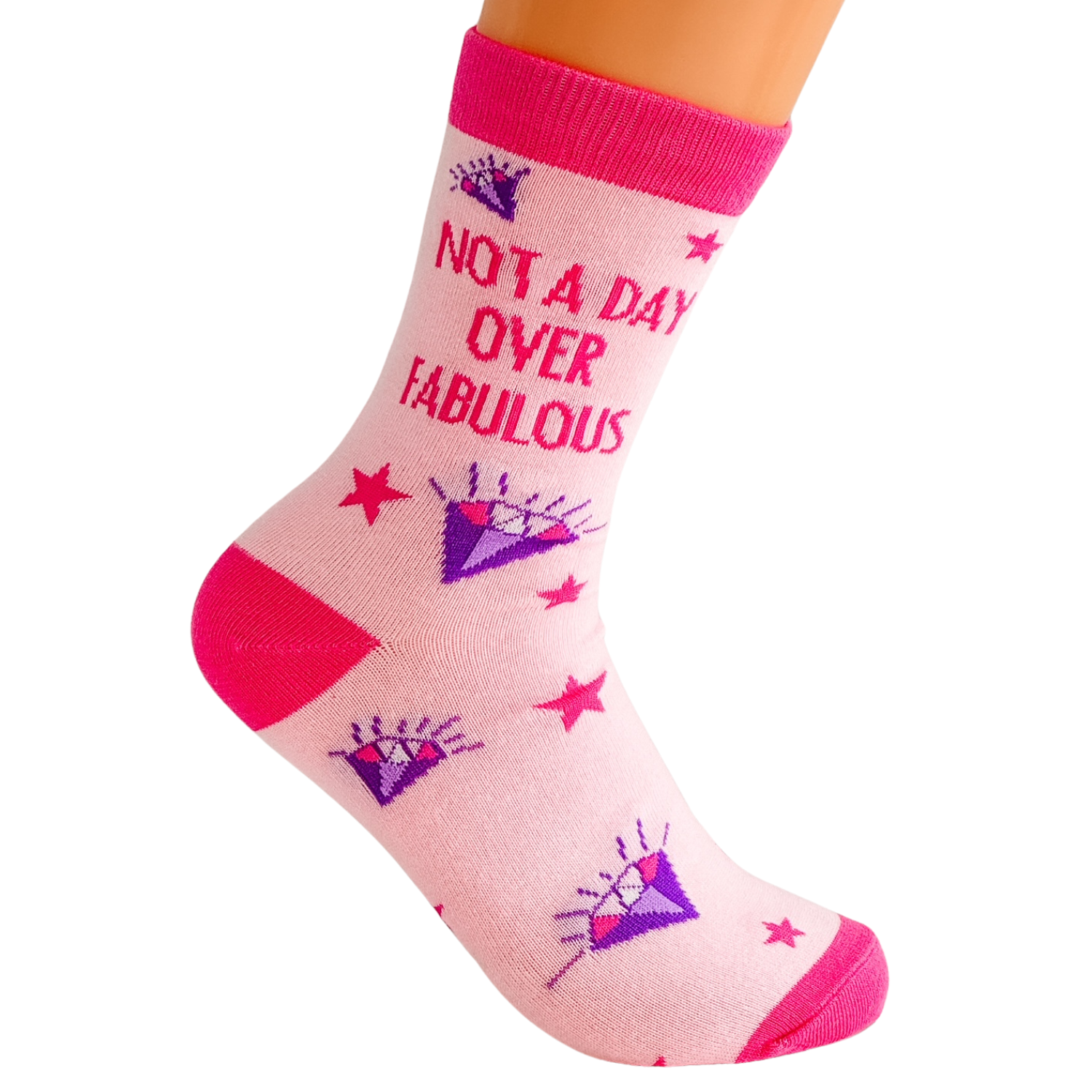 Single pink Not a Day Over Fabulous novelty crew sock with purple diamond and red star design shown worn on a foot against a white background, highlighting the fit and heel shape for everyday wear.