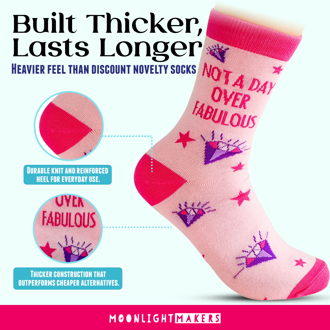 Promotional graphic of pink Not a Day Over Fabulous novelty crew socks with purple diamond and red star design, showing close-up callouts of the reinforced heel and thicker knit construction with Built Thicker, Lasts Longer text and Moonlight Makers branding.