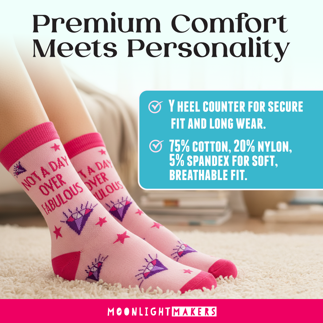 Lifestyle image of pink Not a Day Over Fabulous novelty crew socks with purple diamond and red star design worn indoors on a soft rug, featuring overlay text about Y heel counter and cotton nylon spandex blend with Moonlight Makers branding.