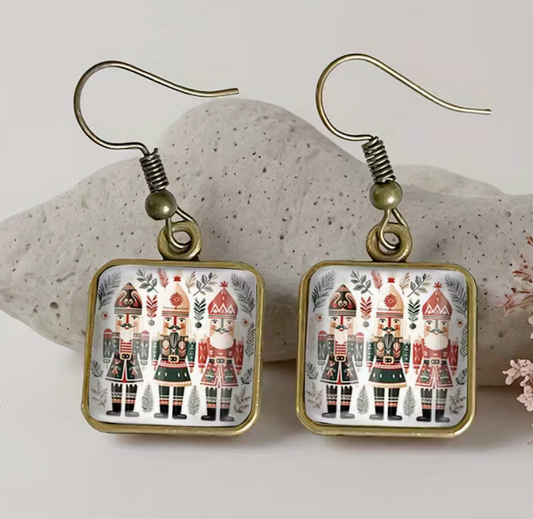 Nutcracker glass dangle earrings displayed on stone background