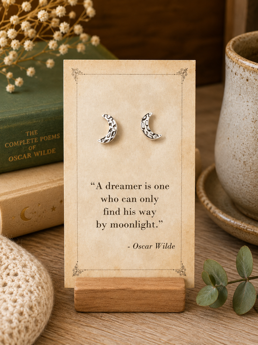 Silver tone patterned crescent moon stud earrings displayed on a vintage Oscar Wilde literary quote card