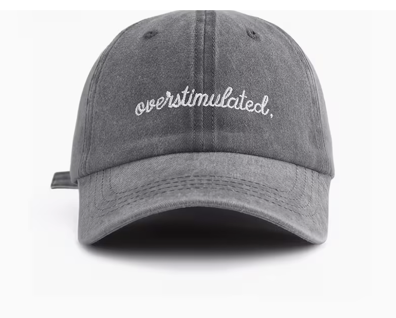 A gray washed baseball cap with 'overstimulated.' embroidered in white script on the front, shown against a plain white background.
