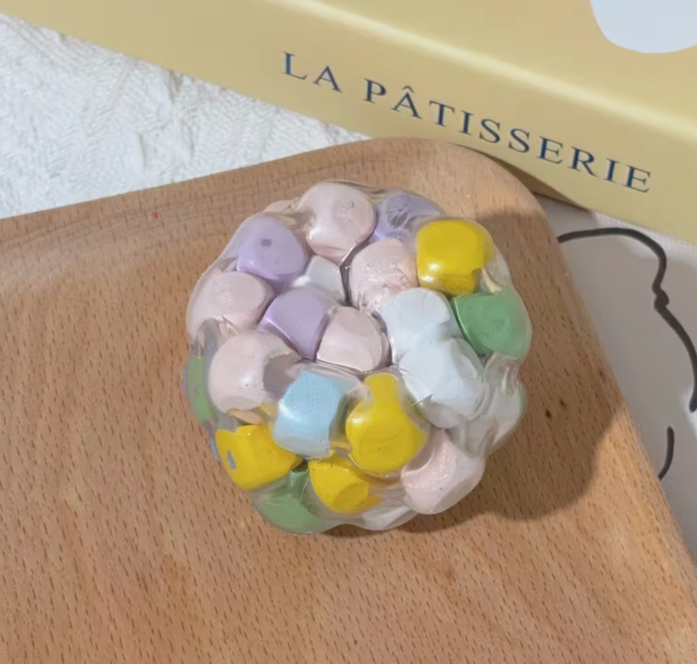 Pastel squishy stress ball with colorful shapes inside a clear flexible shell