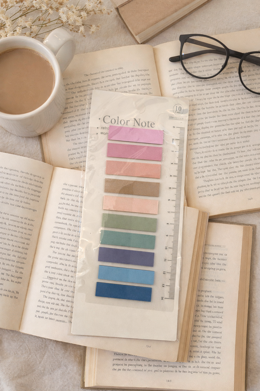 Pastel sticky book tabs labeled Color Note arranged on an open book with a coffee mug and glasses in a cozy reading flat lay.