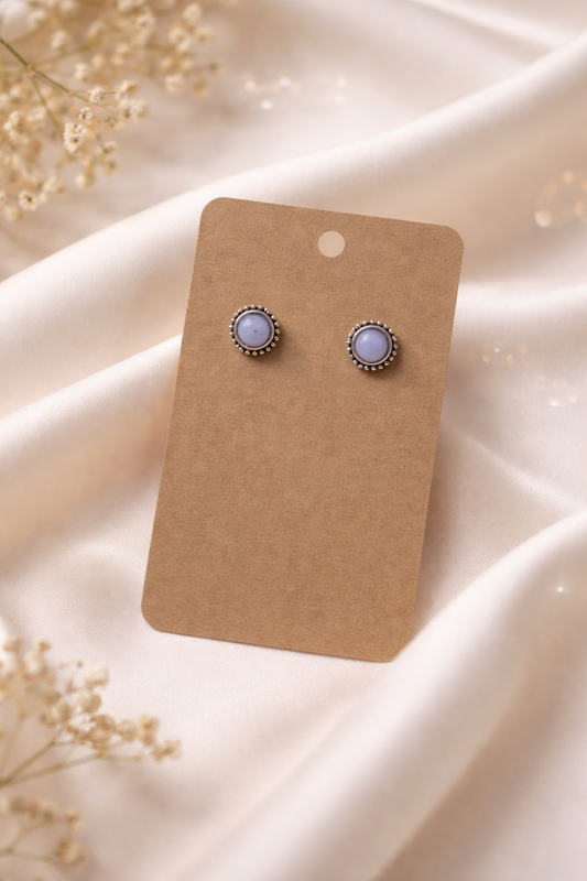 Pearl stud earrings with silver tone setting displayed on a neutral card with a soft light background