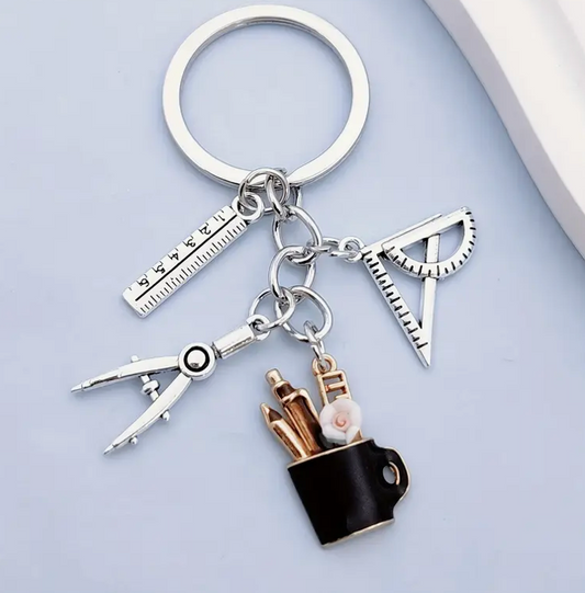 Metal keychain shaped like a mug filled with pens, a protractor, a compass, and a ruler—perfect for teachers and school staff.