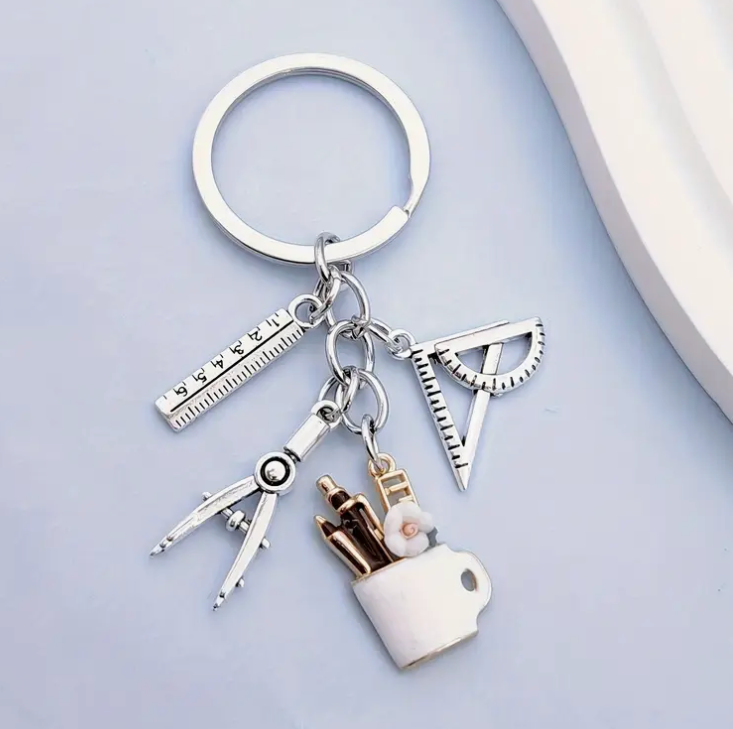 Metal keychain shaped like a mug filled with pens, a protractor, a compass, and a ruler—perfect for teachers and school staff.