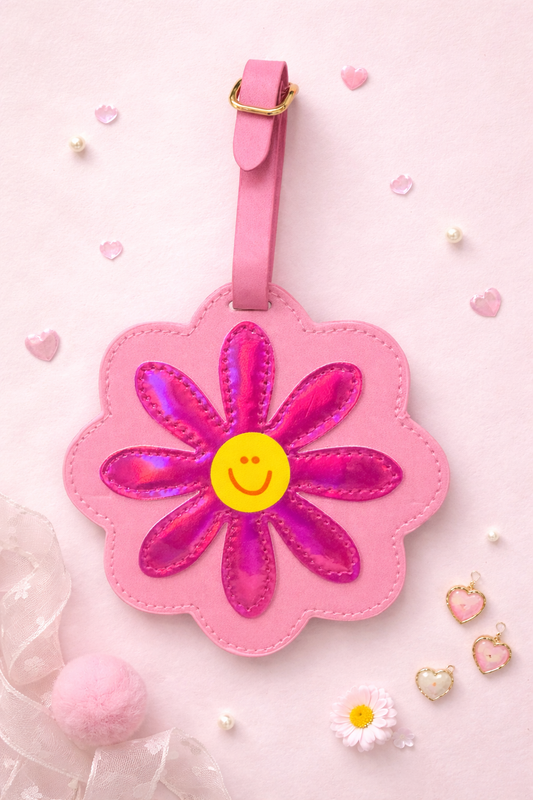 Front view of pink flower-shaped luggage tag with smiley face center
