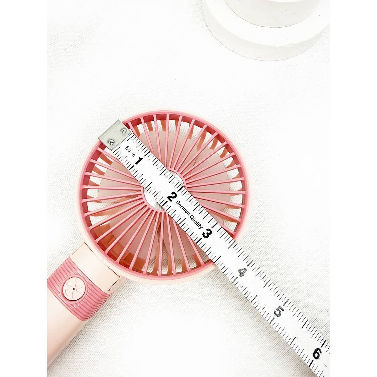 Pink portable handheld fan with ruler showing fan head size