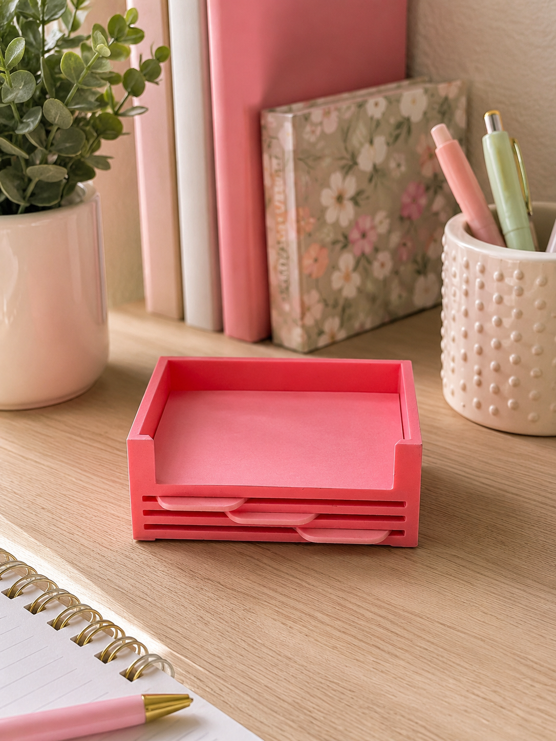 Front view of a pink 3D printed sticky note holder featuring storage for interchangeable stencil inserts.