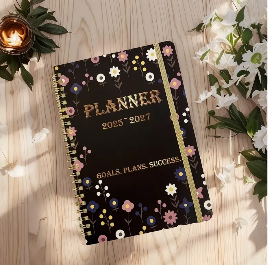 Floral print 2025–2027 monthly planner with double wire binding and elastic closure shown open to a monthly spread.