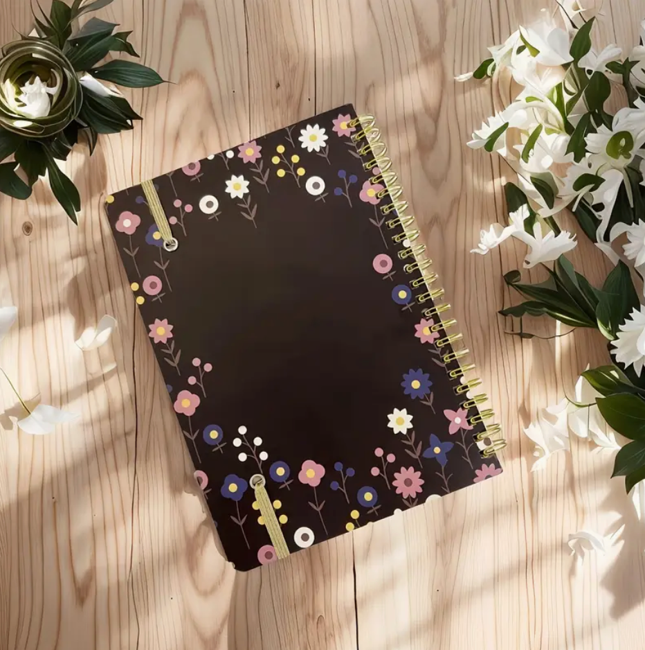 Floral print 2025–2027 monthly planner with double wire binding and elastic closure shown open to a monthly spread.