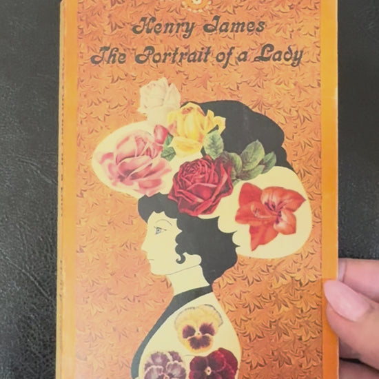 Vintage 1964 Signet Classics paperback edition of The Portrait of a Lady by Henry James displayed on a brass book stand