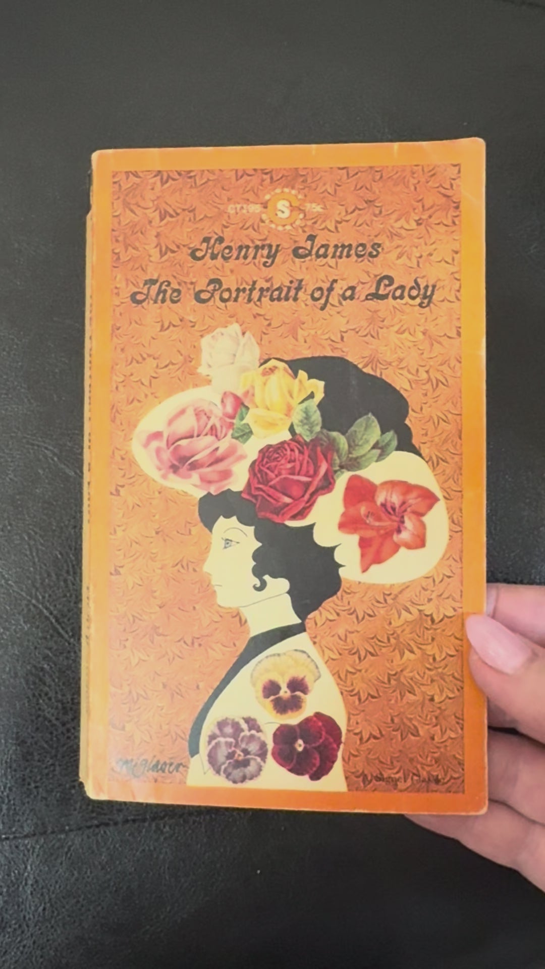 Vintage 1964 Signet Classics paperback edition of The Portrait of a Lady by Henry James displayed on a brass book stand