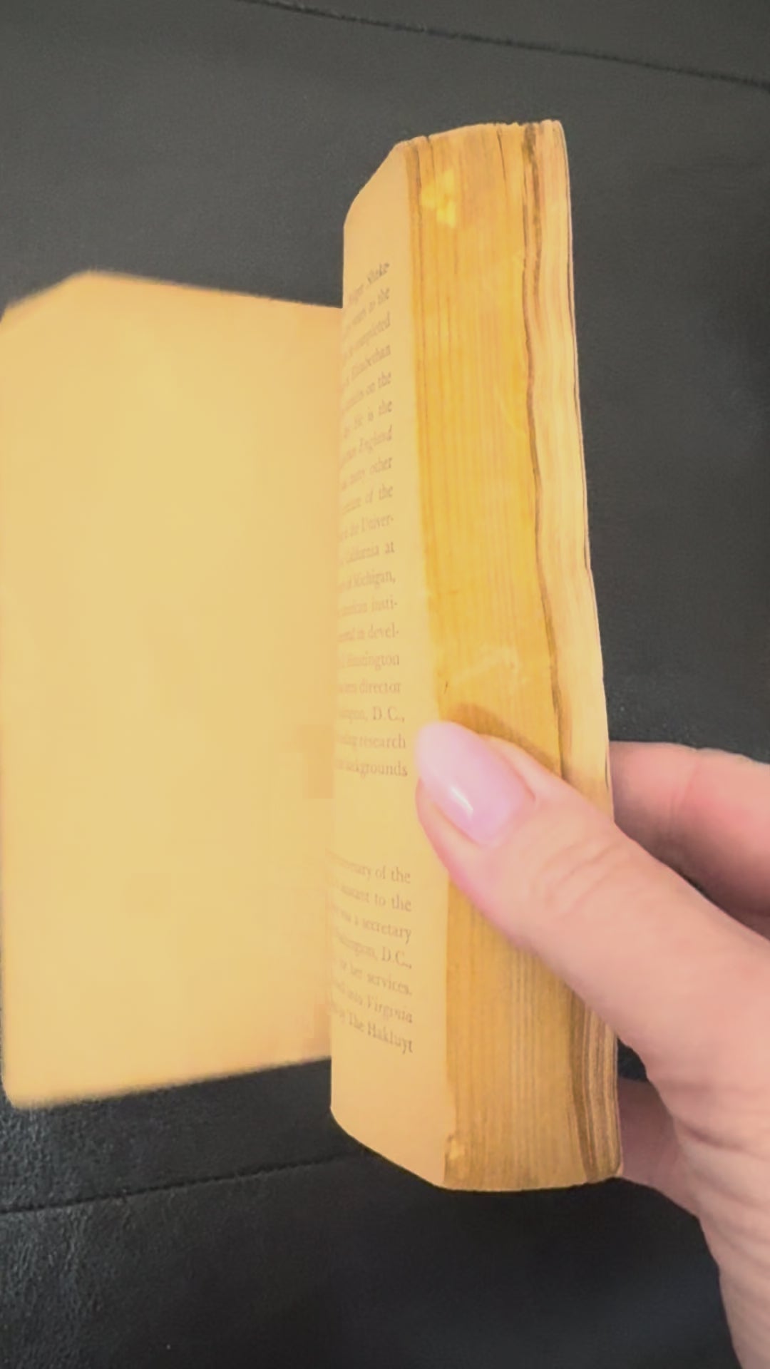 Book titled 'The Merchant of Venice' by William Shakespeare on a wooden stand with a plant in the background.