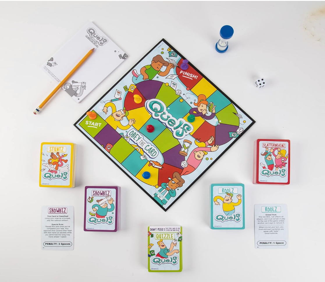 Overhead view of Quelf game setup showing colorful board, challenge cards, timer, die, and player pawns.