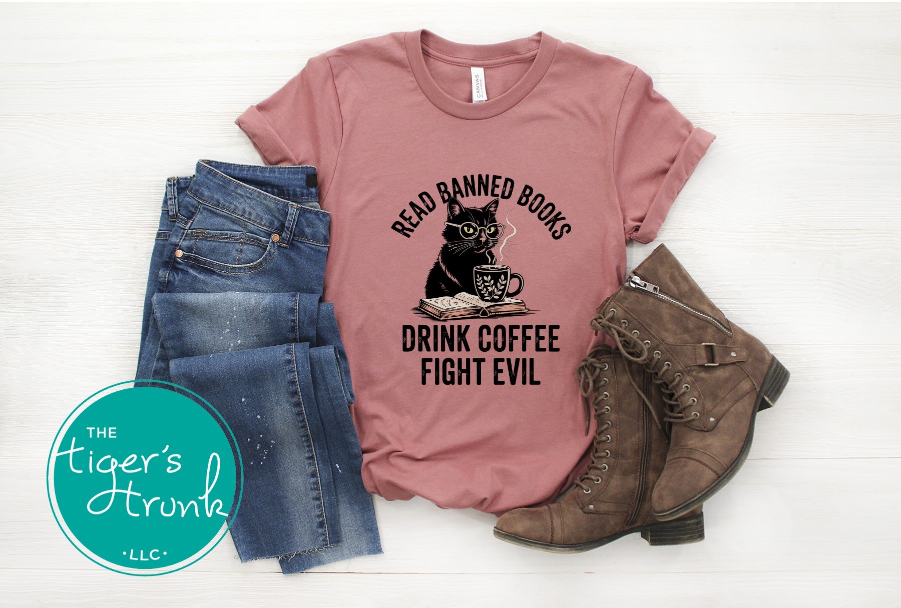 Pink t-shirt with a cat graphic and text, paired with jeans and boots on a white background.