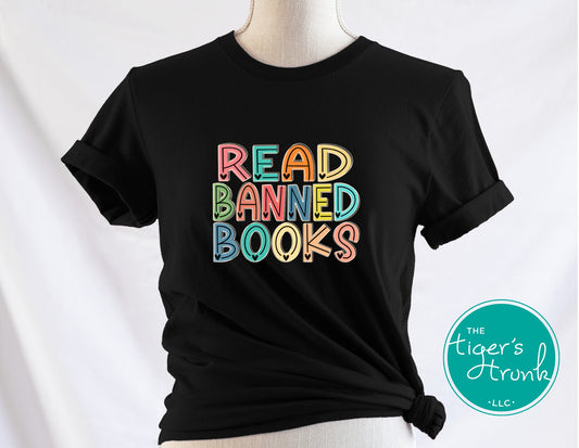 Black t-shirt with colorful 'Read Banned Books' text on a mannequin against a white background, featuring the brand 'The Tiger's Trunk'.