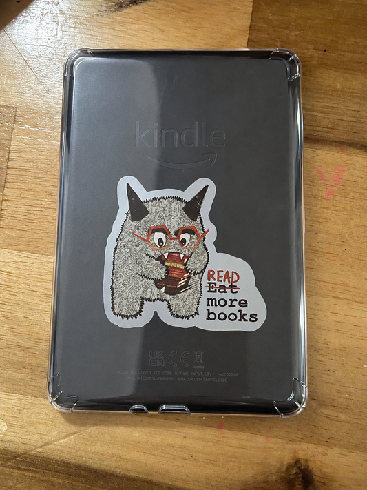 Cute Book Monster character vinyl sticker holding books with the phrase "Read More Books" displayed on the back of a Kindle.