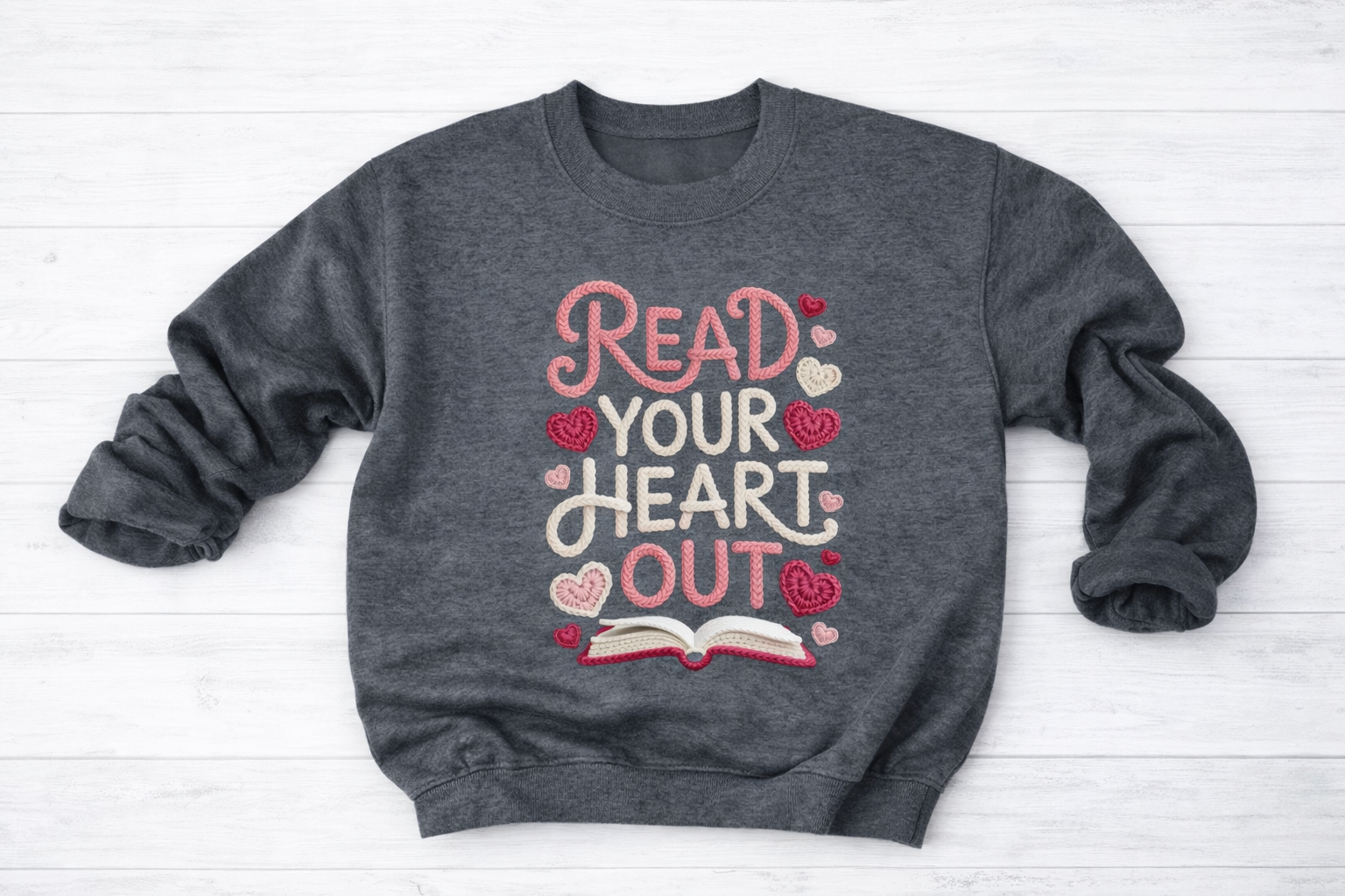 Gray sweatshirt with 'Read Your Heart Out' text on a white wooden surface