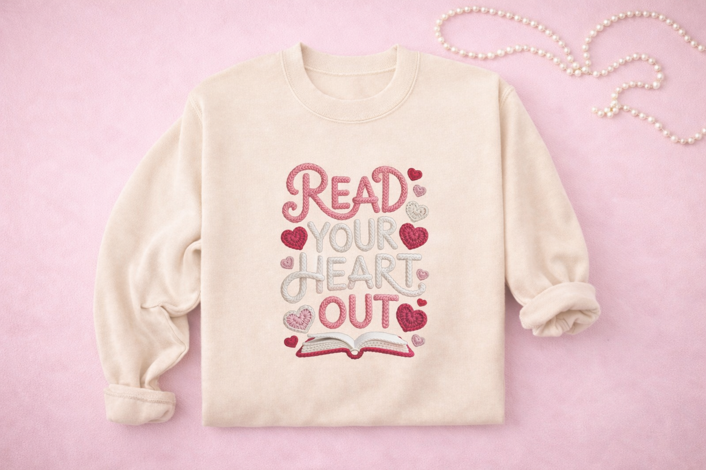Cream-colored sweatshirt with 'Read Your Heart Out' text and hearts on a pink background