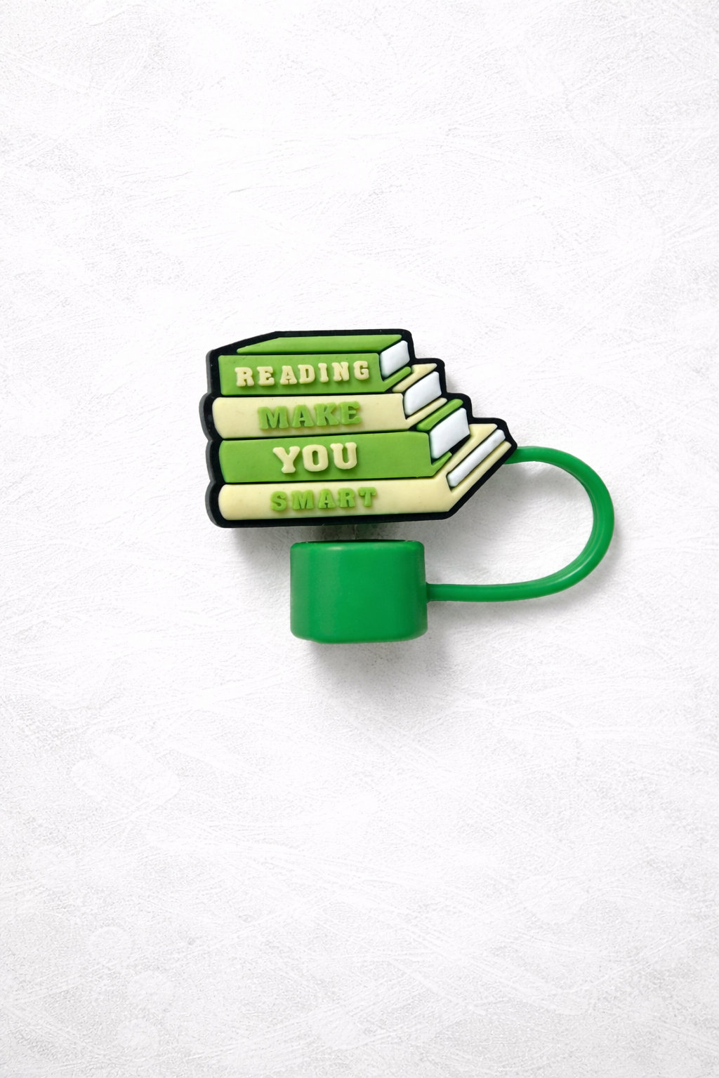 Green silicone straw topper shaped like a stack of books reading Reading Makes You Smart with flexible loop attachment for reusable tumbler straw.
