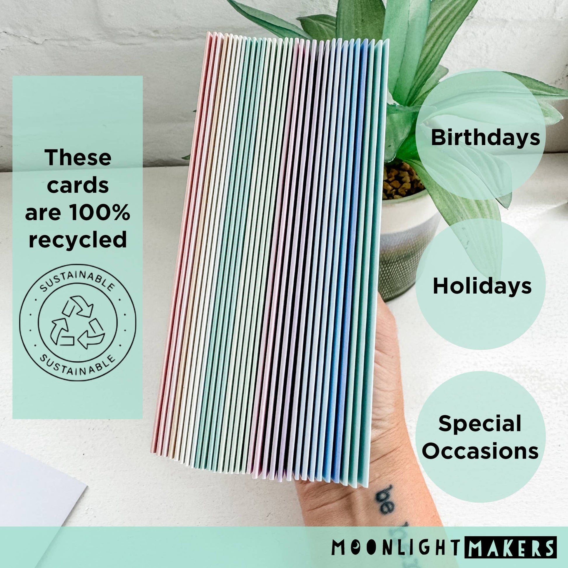 Stack of recycled greeting cards with a hand holding them, labeled for birthdays, holidays, and special occasions, with 'Moonlight Makers' branding.