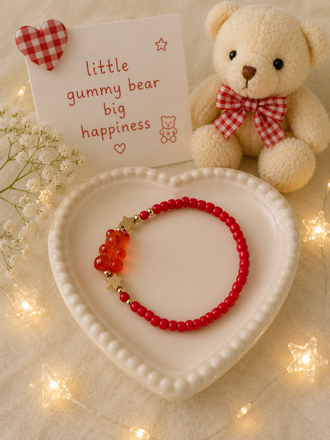 Red stretch bead bracelet with transparent gummy bear charm and gold accents displayed in heart dish
