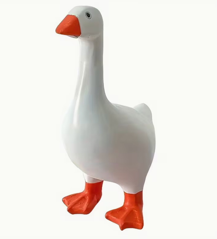 white resin goose figurine with orange beak and feet standing upright on plain background