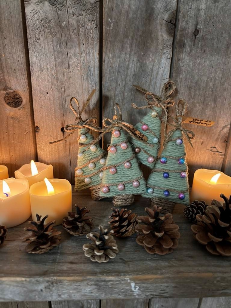 Group of handmade yarn Christmas tree ornaments styled with pinecones and candles