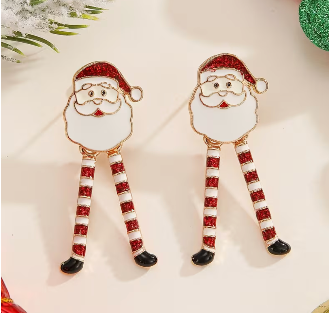 Pair of Santa Claus drop earrings with red glitter legs and white enamel faces displayed on festive background