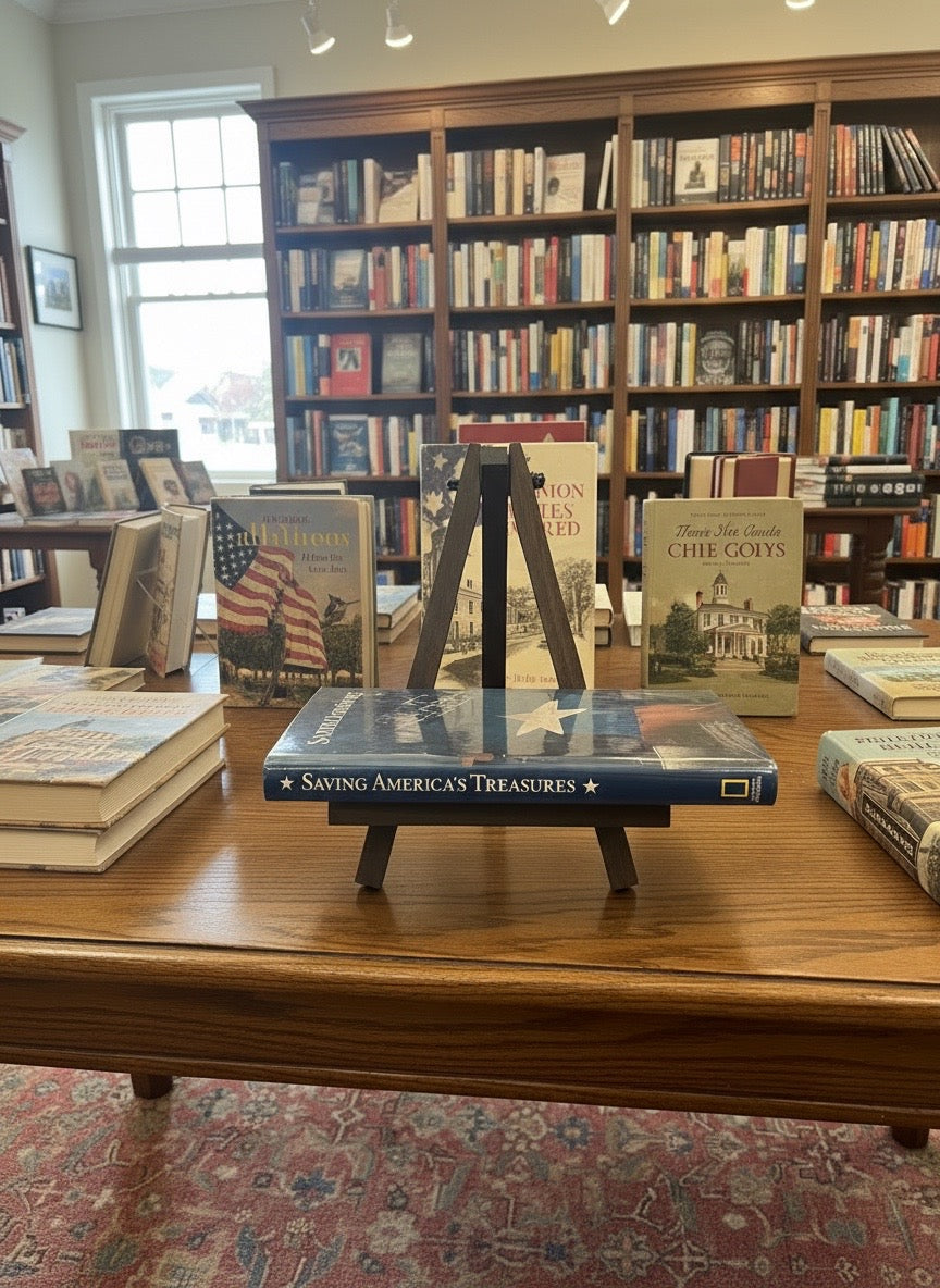 Spine of Saving America's Treasures hardcover book displayed on a wooden easel in a bookstore.