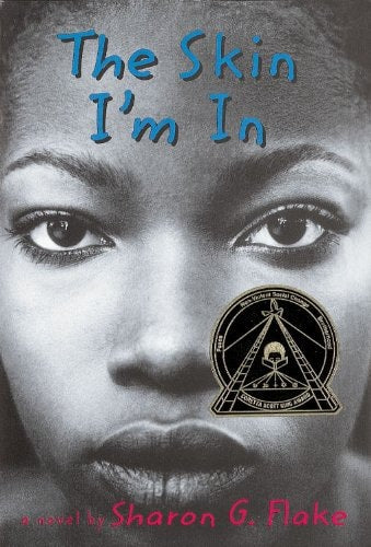 This image features the cover of the hardback edition of "The Skin I'm In" by Sharon Flake. The cover displays a striking portrait of a young girl with a serious expression, her eyes reflecting resilience and strength.