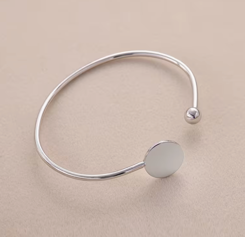 Silver-tone adjustable open cuff bracelet featuring a smooth round blank disc ideal for personalization or custom engraving.