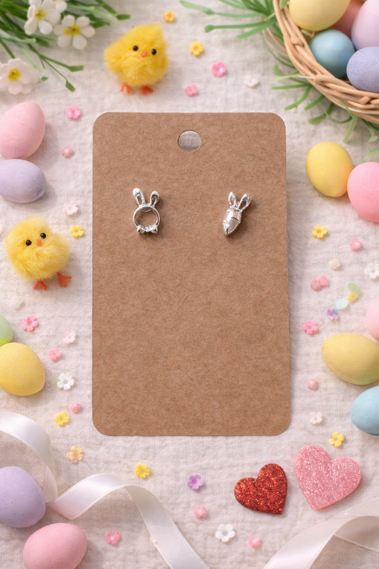 Silver bunny and carrot stud earrings displayed on jewelry card with Easter decor