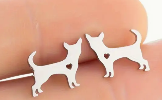 Silver dog-shaped earrings on a finger