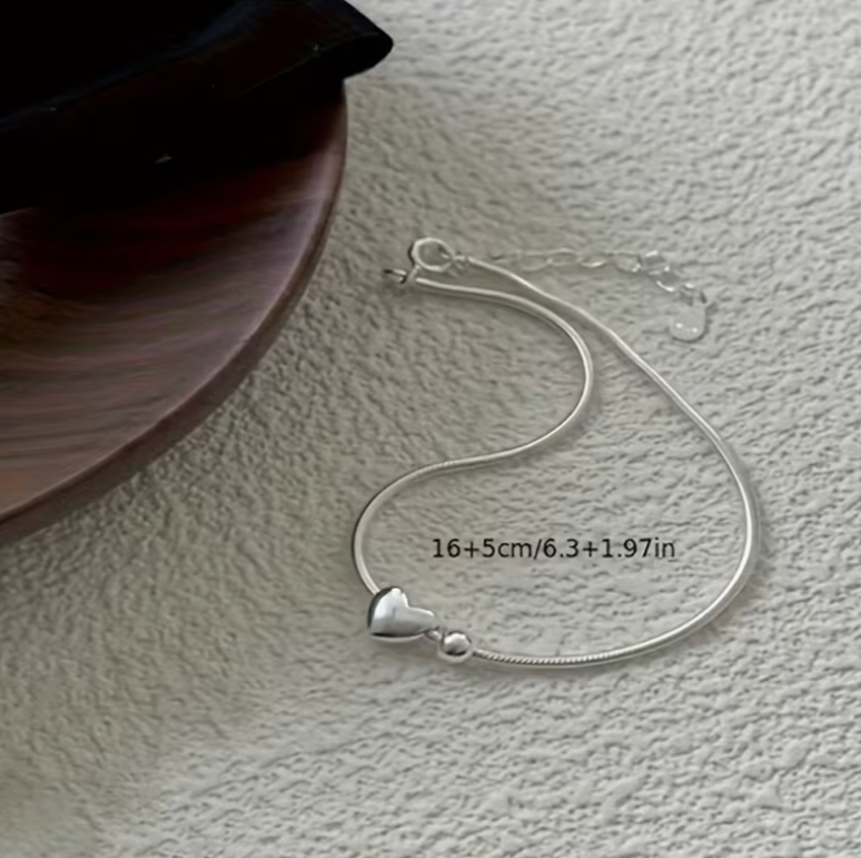 Silver minimalist heart bracelet with snake chain and adjustable clasp displayed flat