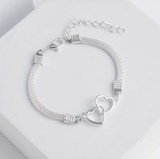 Silver heart chain bracelet with linked hearts displayed on neutral background