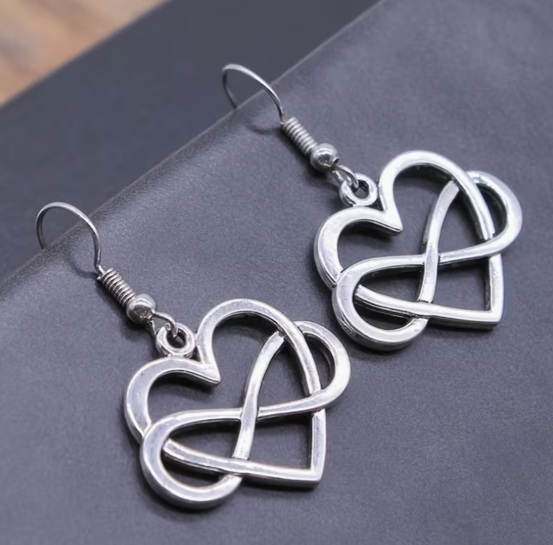 Silver infinity heart earrings with intertwined love symbol design on dark background