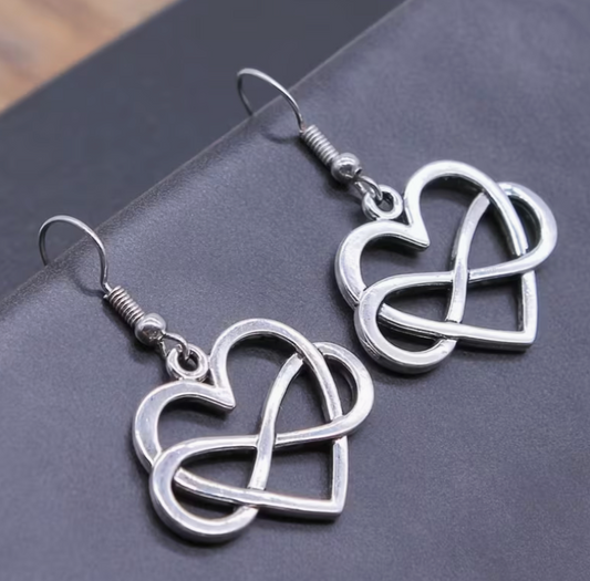 Silver infinity heart earrings with intertwined love symbol design on dark background
